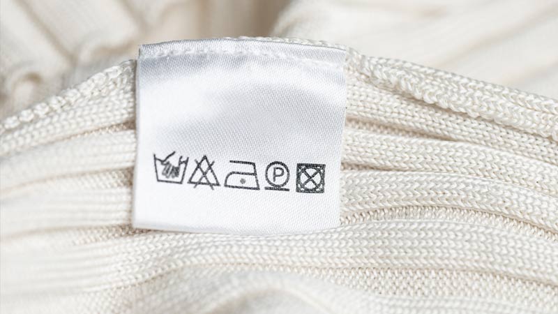 Etiqueta de uma peça de roupa branca com os símbolos de cuidados ao lavar e engomar